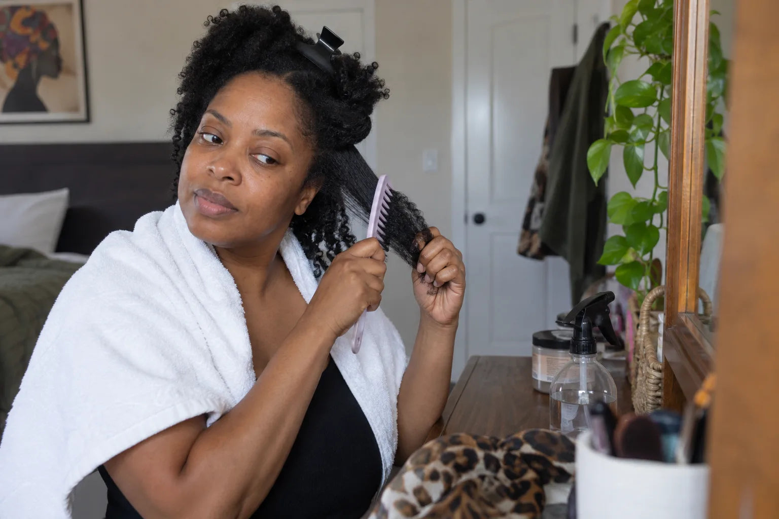 A woman gently detangling a section of natural coily hair at home